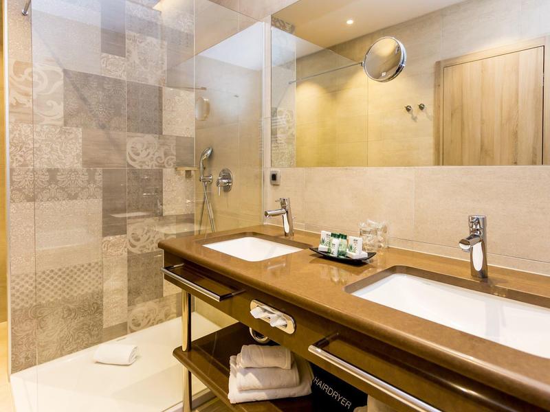 Modernes Badezimmer mit Doppelwaschbecken und Glasdusche in hellen Tönen.