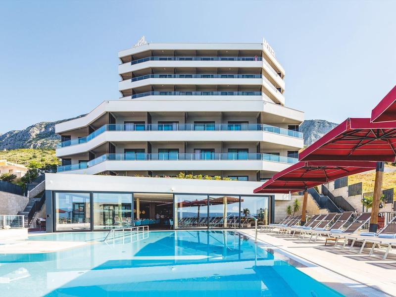 Modernes Hotel mit mehreren Etagen und großem Außenpool unter klarem Himmel