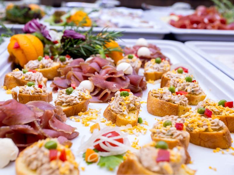 Verschiedene belegte Brötchen und Wurstplatten auf einem weißen Buffettisch angerichtet.