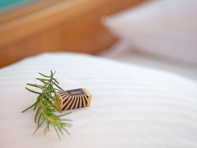 Un piccolo pezzo di cioccolato con un rametto di rosmarino su lenzuolo bianco.