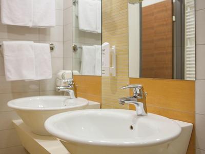 Camera d'hotel moderna con letto matrimoniale, parquet e arredi sobri.