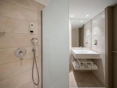 Camera d'hotel moderna con letto matrimoniale, decorazioni blu e televisore a parete.