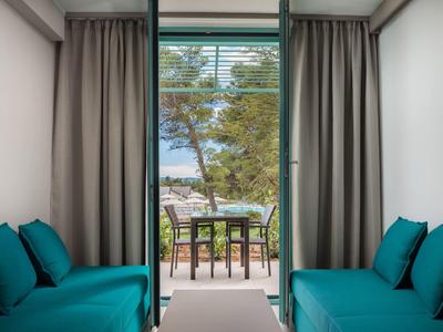 Vista da una stanza con divani blu su una terrazza con tavolo e sedie di fronte alla natura verde.