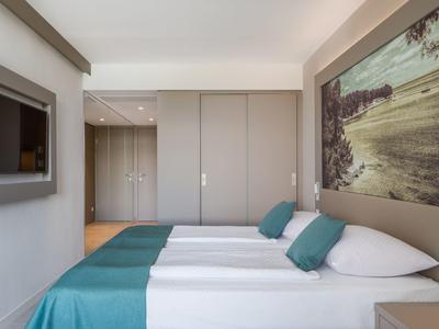 Camera d'hotel moderna con due letti, coperte blu e una grande immagine sulla parete.