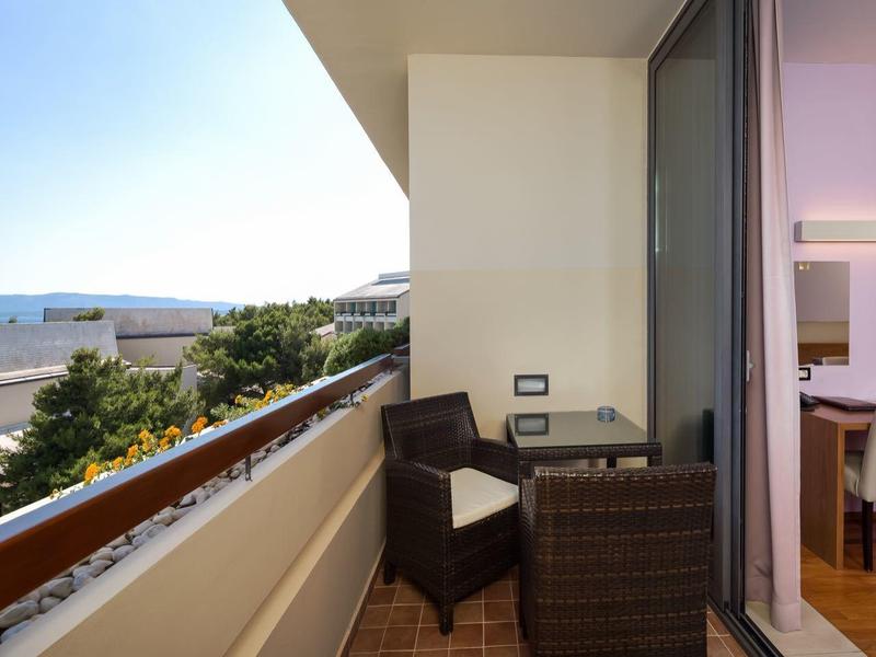 Balcone con mobili da esterno e vista sul mare adiacente a una sala da pranzo moderna