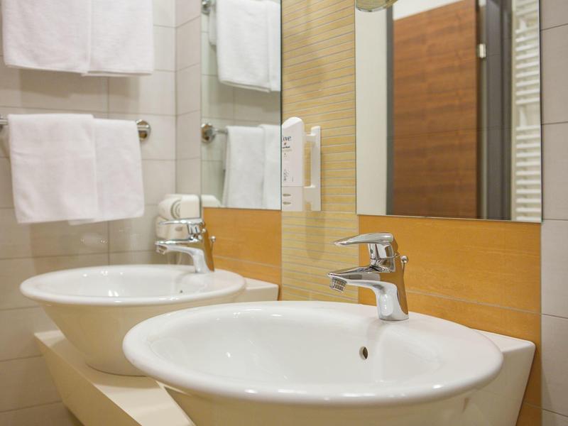 Camera d'hotel moderna con letto matrimoniale, parquet e arredi sobri.