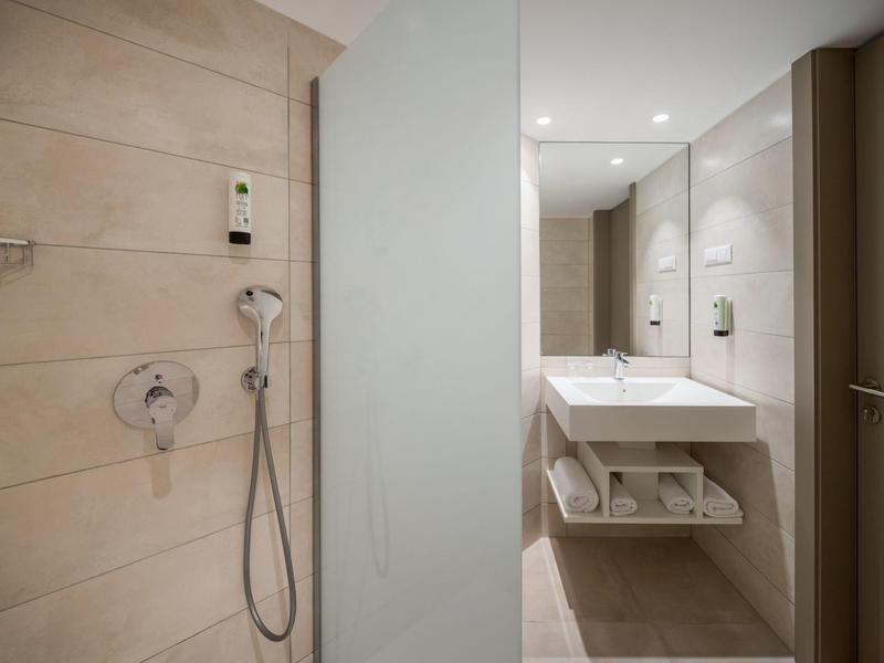 Camera d'hotel moderna con letto matrimoniale, decorazioni blu e televisore a parete.