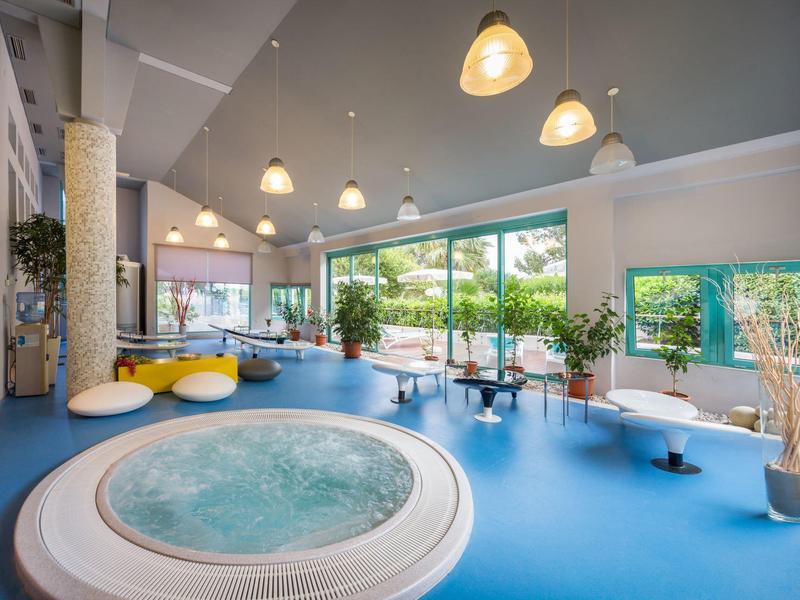 Area benessere moderna con idromassaggio rotondo, pavimento blu e grandi finestre.