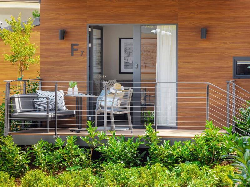 Moderní hotelová terasa s posezením před dřevěnou fasádou a zelenou zahradou