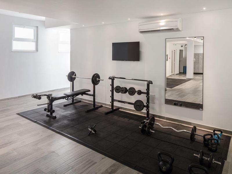 Malá posilovna s činkami, osami a lavicí na černé podložce.