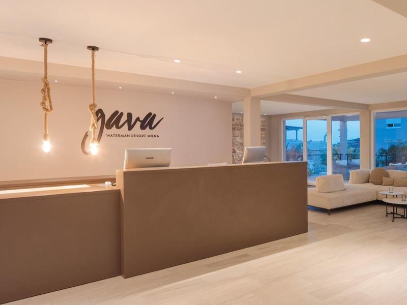 Moderní hotelová hala s recepcí, pohodlným salonkem a velkými okny.