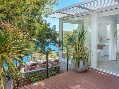 Balkon mit Holzboden und Pflanzen mit Blick auf das Meer und eine Lounge-Ecke
