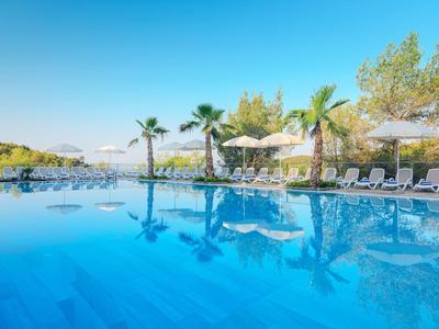 Klare, blaue Poollandschaft mit Liegestühlen, Sonnenschirmen und Palmen an einem sonnigen Tag.