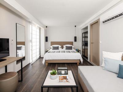 Modern eingerichtetes Hotelzimmer mit Doppelbett, Sofa, Fernseher und großem Fenster.