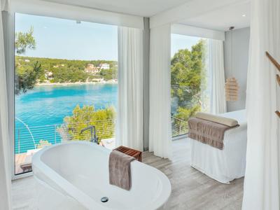Bagno moderno con vasca da bagno e vista sul mare e natura verde.