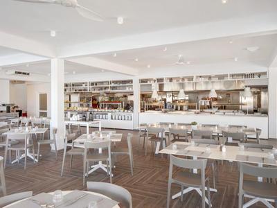 Ampia sala ristorante con tavoli rotondi, sedie moderne e arredamento minimalista.