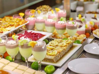 Buffet con dessert freddi, pasticcini e insalate, in un ambiente elegante.