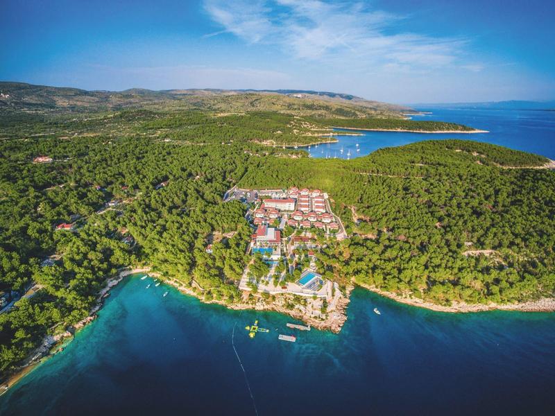 Località balneare circondata da fitta vegetazione con spiaggia e mare blu.