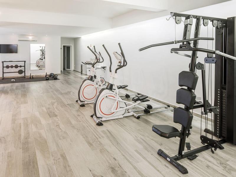 Palestra moderna con cyclette e macchina per il sollevamento pesi, pavimento chiaro in legno.