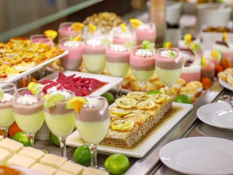 Buffet con dessert freddi, pasticcini e insalate, in un ambiente elegante.