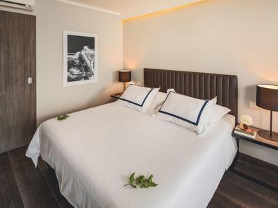 Modernes Hotelzimmer mit großem Bett, braunen Möbeln und dezentem Licht.