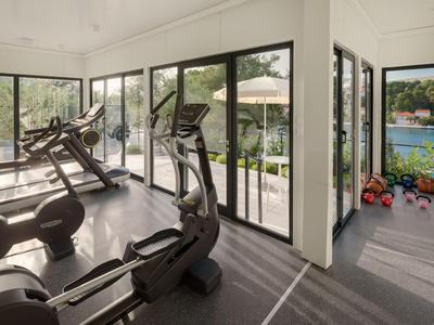 Moderne sportschool met loopbanden en gewichten met uitzicht op een meer en tuin.