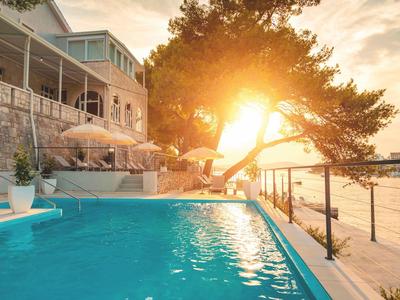 Una piscina accanto a un hotel con vista sul mare al tramonto.