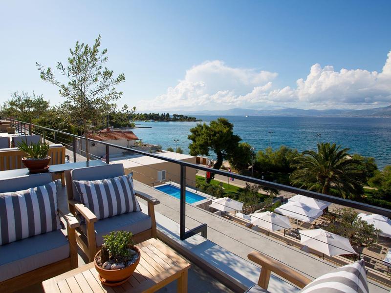 Terras met comfortabele zitplaatsen en uitzicht op zee en palmbomen.