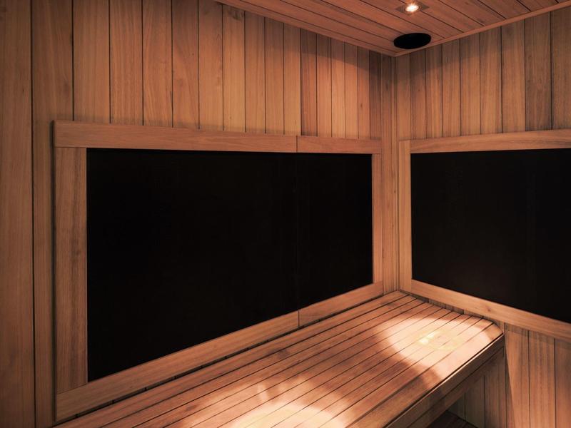 Houtsauna met bank en twee grote raamachtige panelen aan de muren.