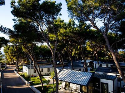 Bungalow tra alti alberi in un soleggiato villaggio turistico.