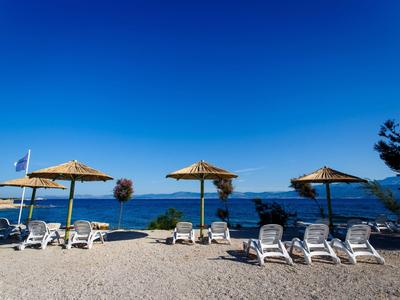 Strand met ligstoelen en parasols onder heldere blauwe lucht en zee