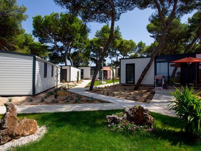 Maisons de vacances modernes avec terrasse et jardin dans une station hôtelière boisée.