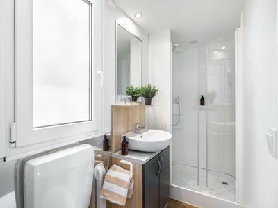 Salle de bain compacte avec douche, lavabo, WC et fenêtre au design moderne.