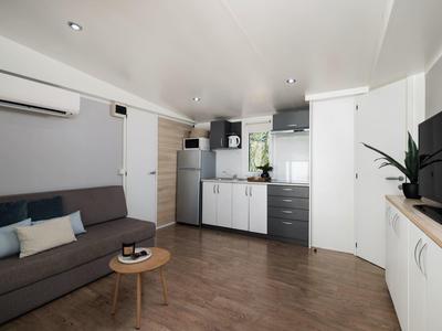 Espace séjour avec canapé, placard de cuisine et télévision dans un appartement moderne