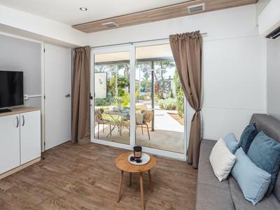 Salon moderne avec terrasse, canapé, TV et parquet en bois dans un appartement de vacances.