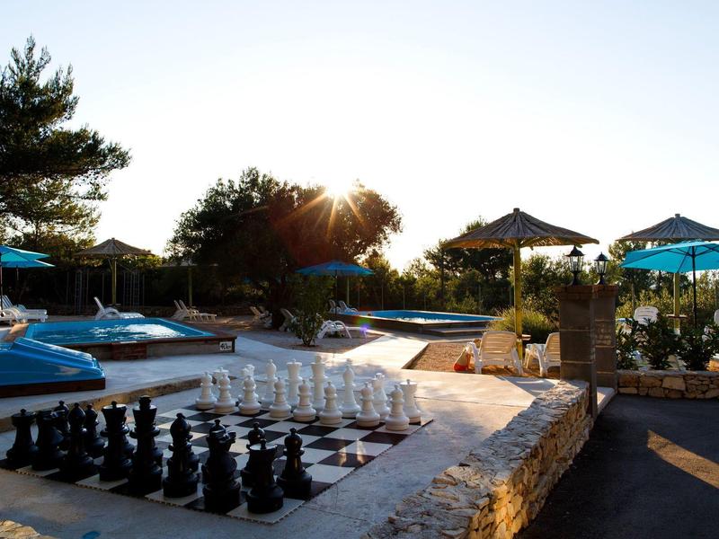 Echiquier et chaises longues près de la piscine dans un complexe de vacances en plein air au coucher du soleil.
