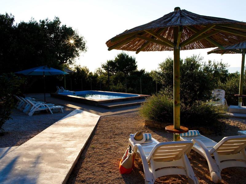 Chaises longues sous un parasol près d'une piscine extérieure au coucher du soleil.