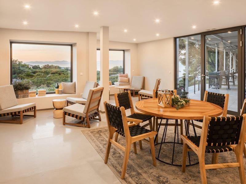 Salle à manger et salon lumineux avec meubles en bois et grande fenêtre avec vue.