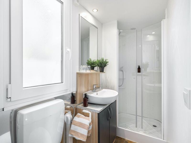 Salle de bain compacte avec douche, lavabo, WC et fenêtre au design moderne.