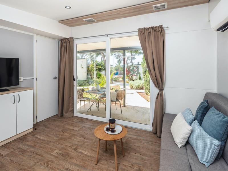 Salon moderne avec terrasse, canapé, TV et parquet en bois dans un appartement de vacances.