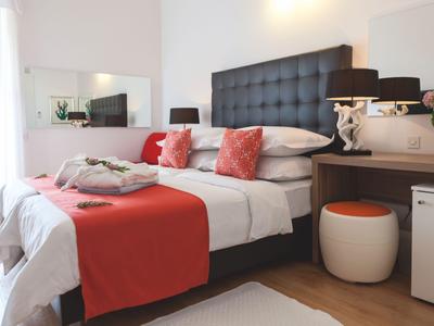 Nowoczesny pokój hotelowy z łóżkiem podwójnym, czerwonymi akcentami i praktycznym biurkiem.