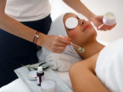 Donna rilassata durante un trattamento viso in un hotel spa, con crema e dischetti.