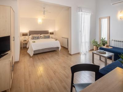 Camera d'hotel luminosa con letto matrimoniale, pavimento in legno e arredamento moderno.