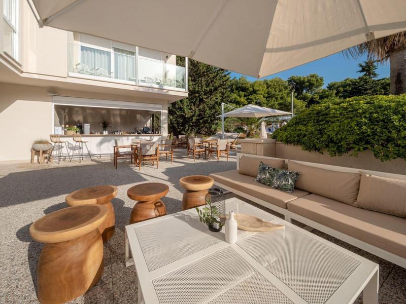 Area esterna con divani, tavoli e ombrelloni in un giardino d'hotel.