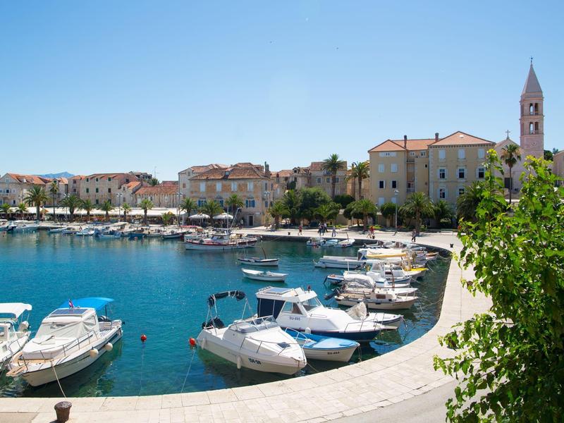 Piccolo porto con barche bianche davanti al lungomare di una città costiera storica