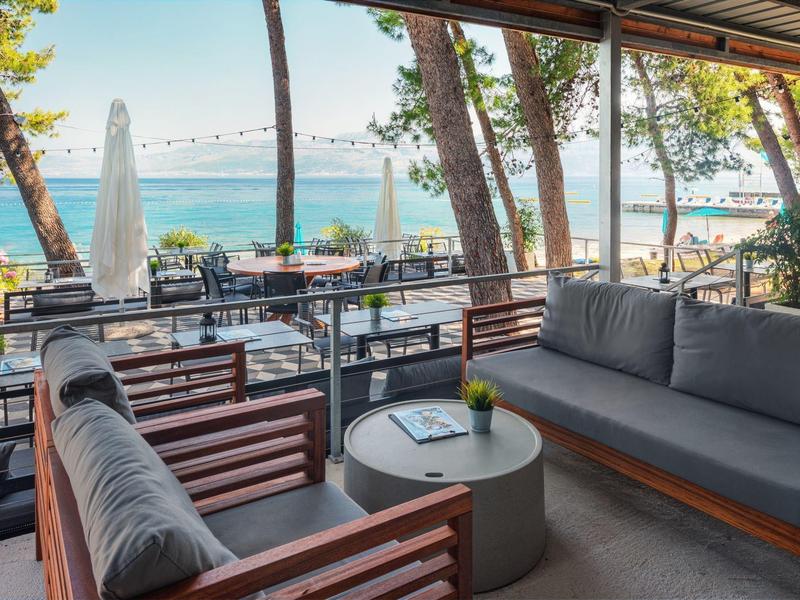 Angolo salotto esterno accogliente con vista sul mare e sulla spiaggia in un ambiente alberghiero rilassato.