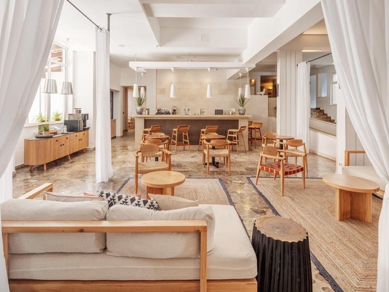 Lounge moderna e luminosa con mobili in legno e aree salotto confortevoli in un hotel.