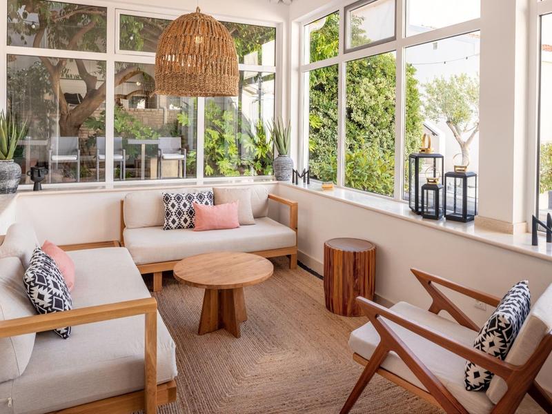 Veranda luminosa con mobili in legno confortevoli e molte piante per momenti di relax.