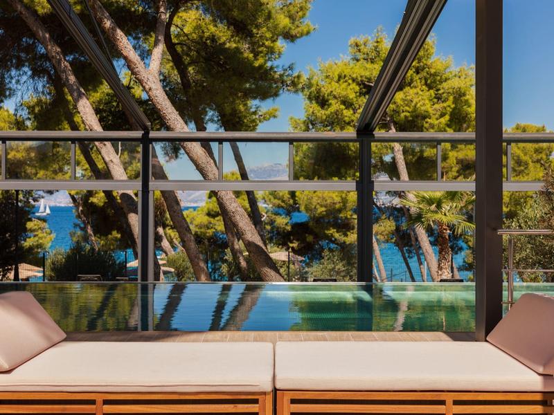 Terrazza con panca, piscina e alberi con vista sul mare.