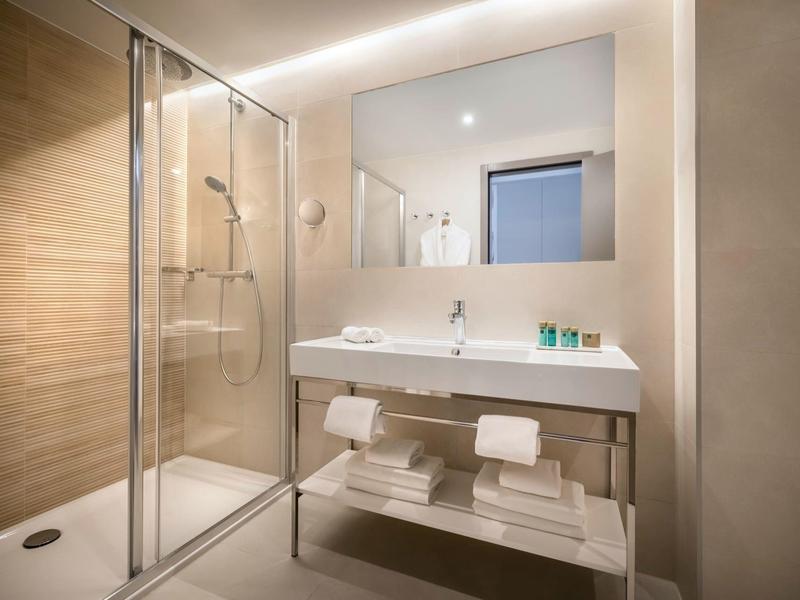 Moderne Hotelbar mit langer Theke, vielen Flaschen und Gläsern, Barkeeper mit rotem Hut.